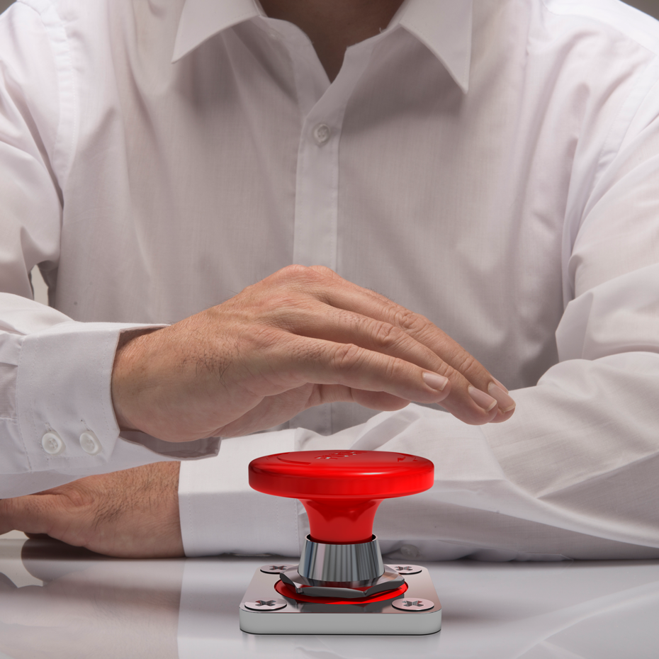 Stratégie de marque et direction éditoriale — VISUELROUGE Main en chemise blanche au-dessus d'un bouton rouge sur un support métallique.