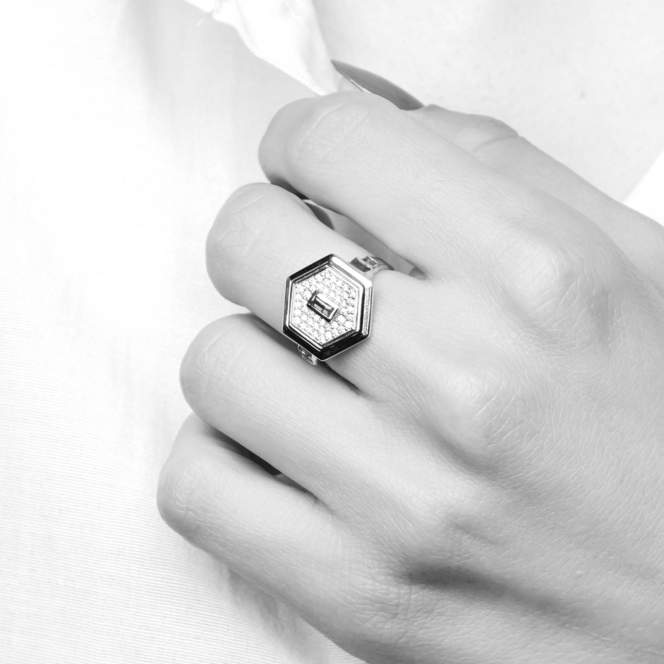 VISUELROUGE – Agence de communication et design graphique Bague hexagonale portée sur une main, avec un design élégant en noir et blanc.