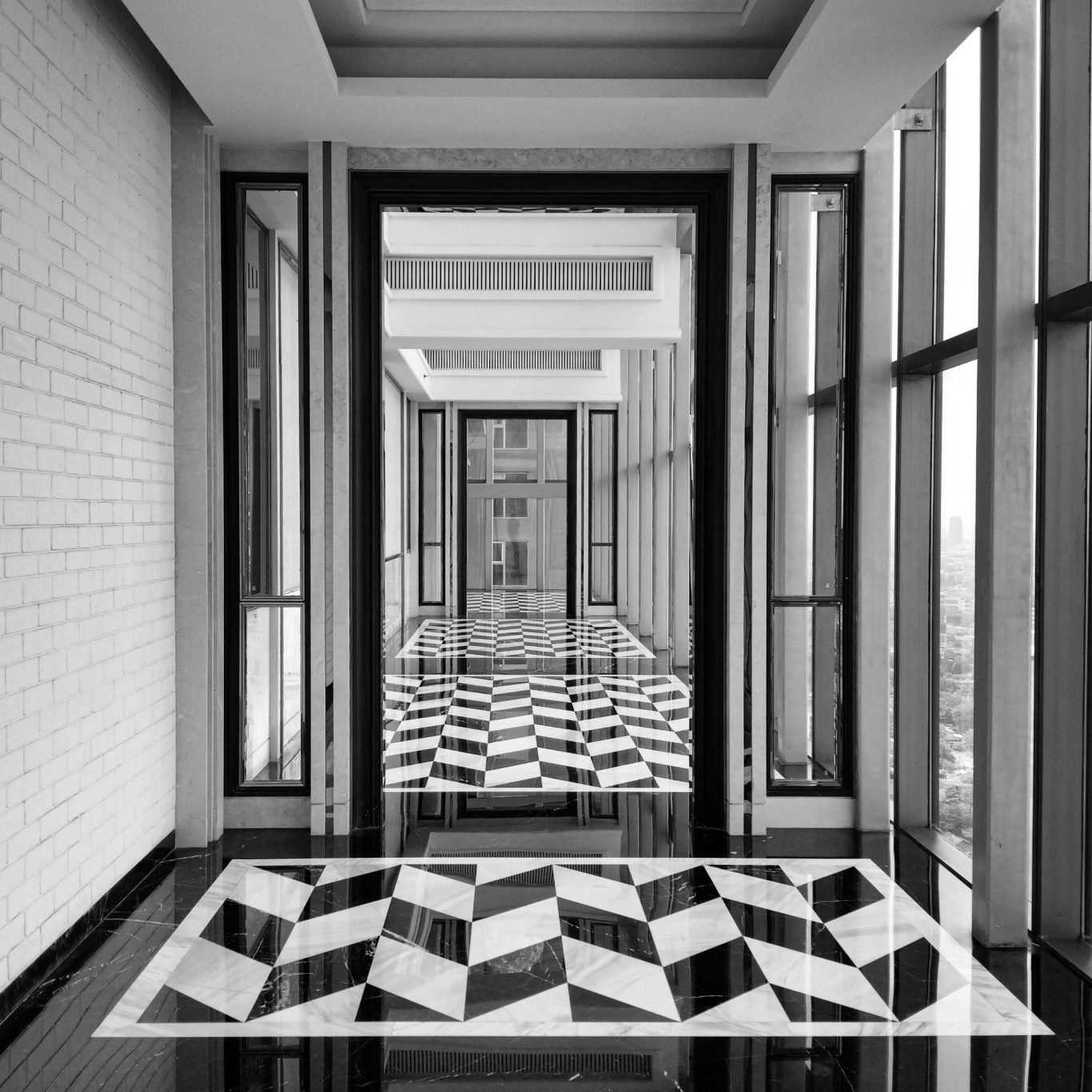 VISUELROUGE – Agence de communication et design graphique Vue d'un couloir élégant avec un sol en motifs géométriques noir et blanc.
